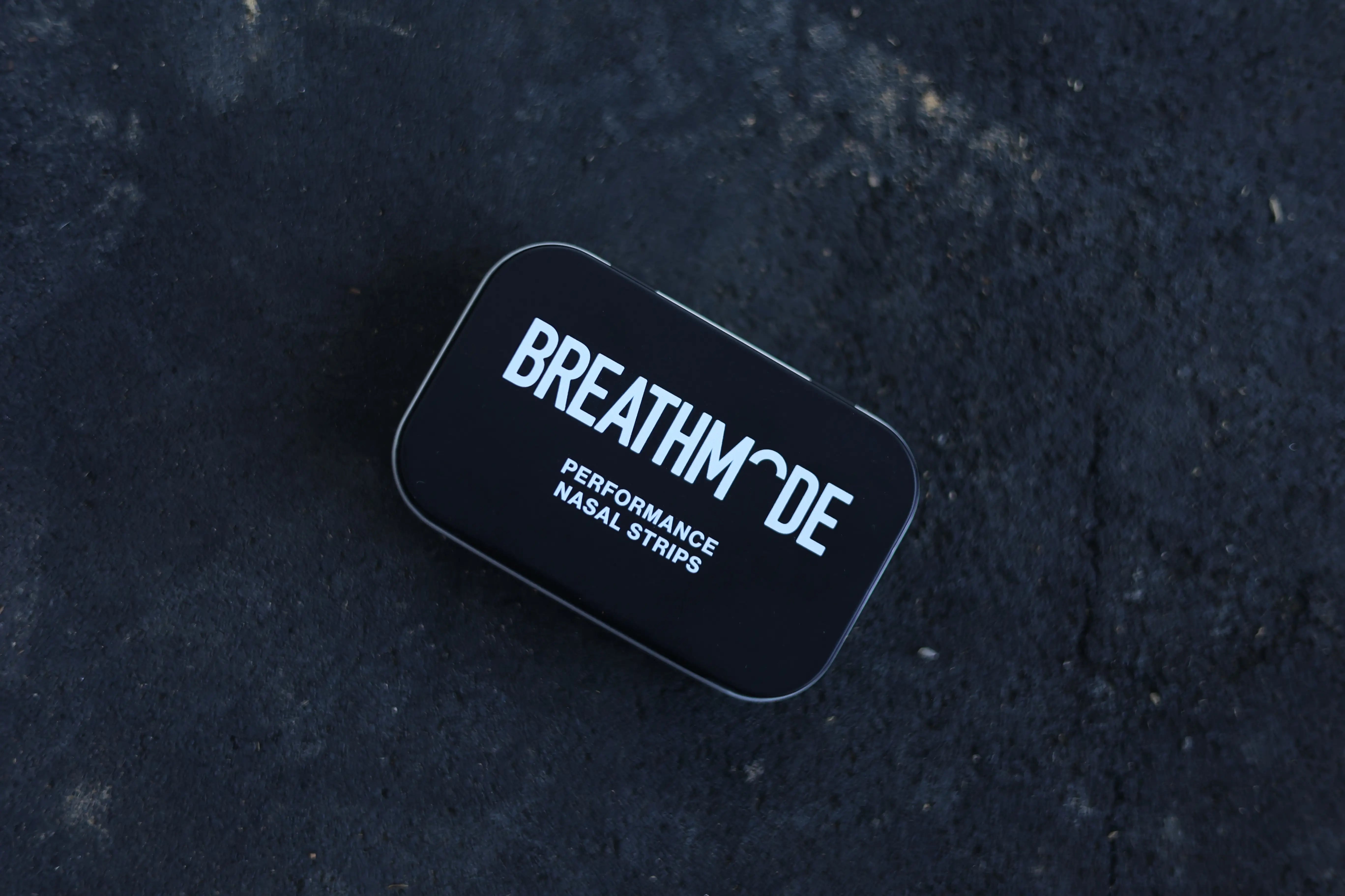 A topdown show of a black BREATHMODE performance nasal strips tin 