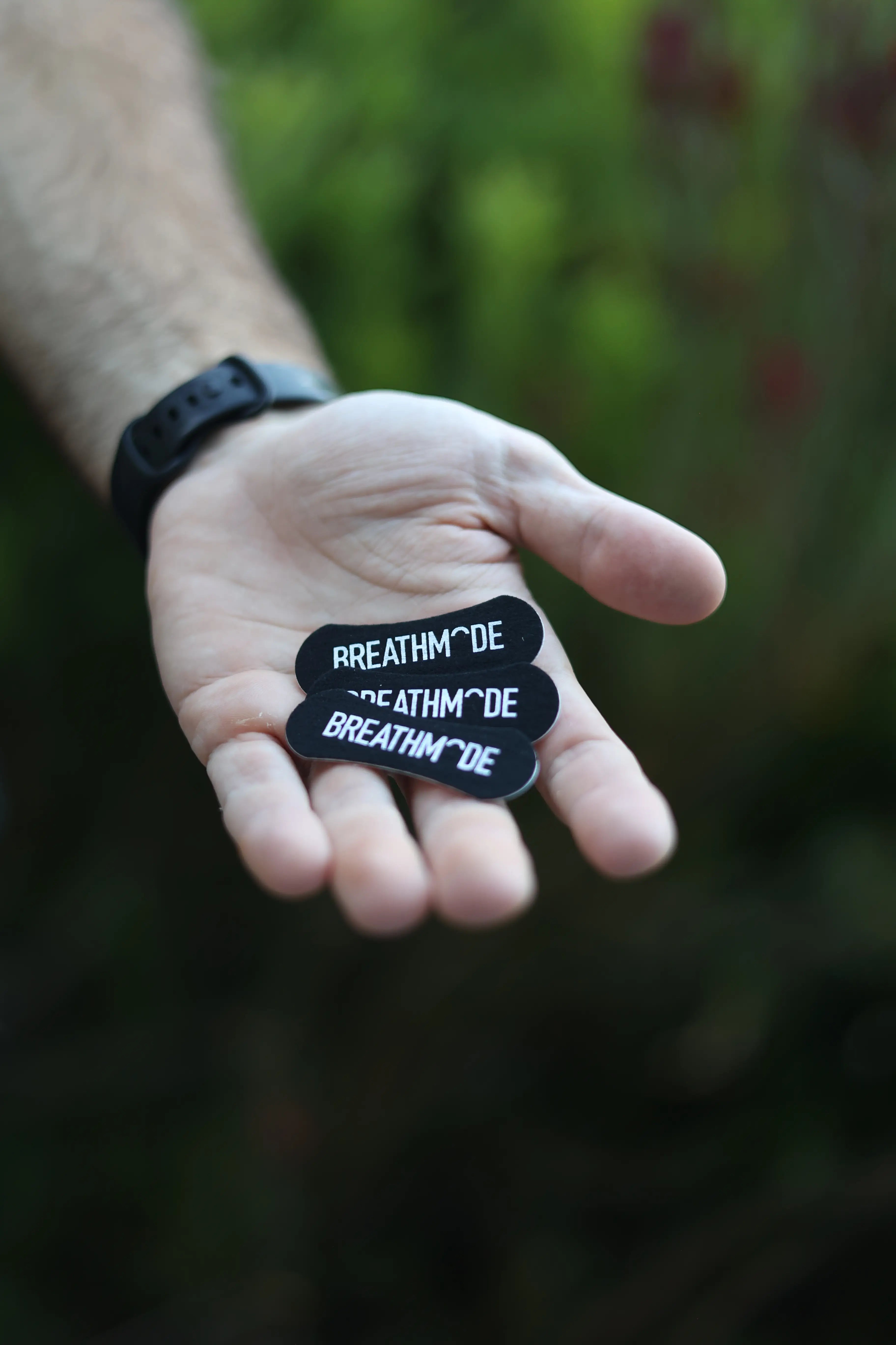 Three BREATHMODE sleep nasal strips held in an outstretched hand 