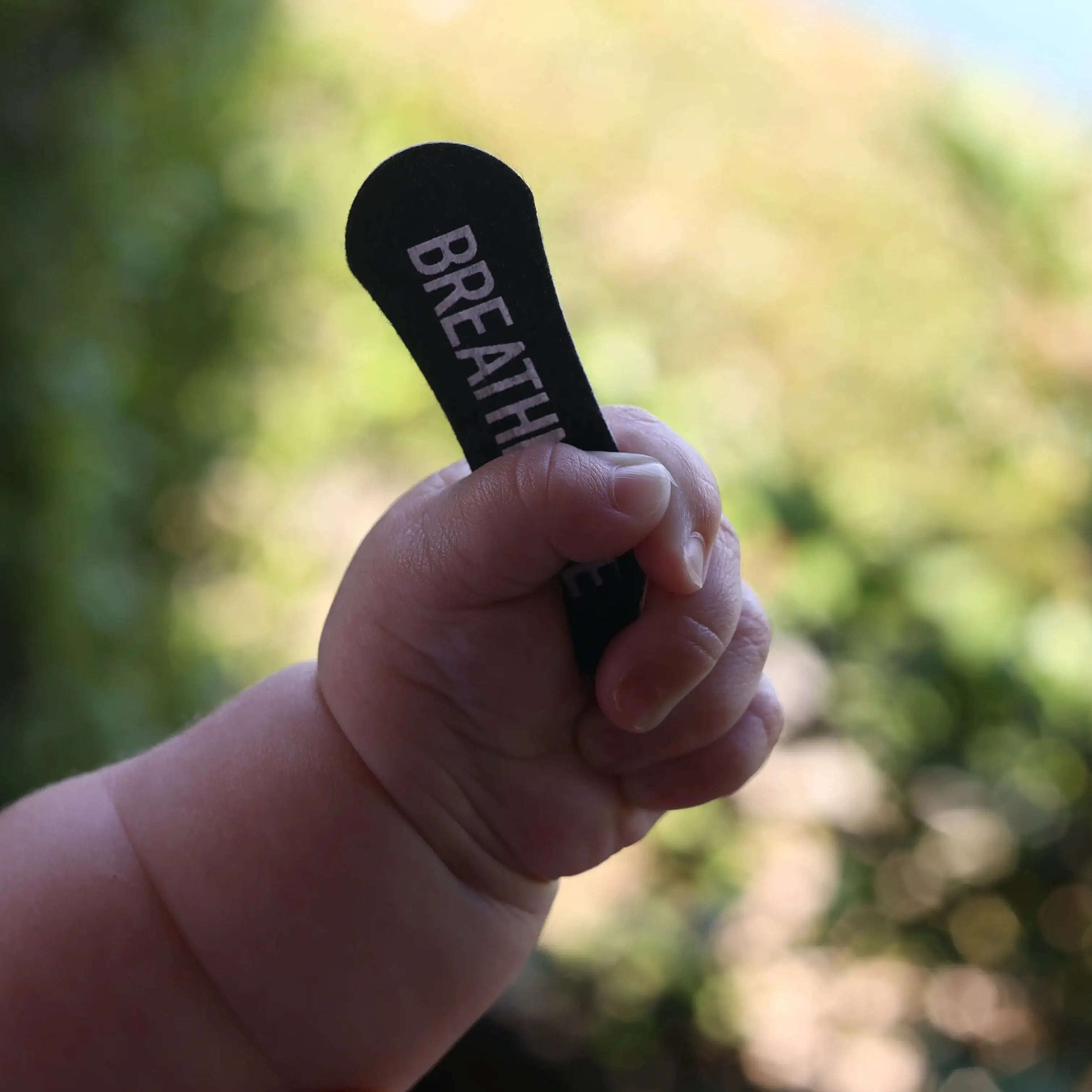 Little O's hand holding a BREATHMODE Sleep Nasal Strip. She is part of the BREATHMODE team